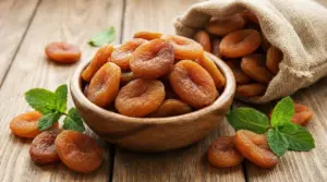 Ciotola di albicocche secche su un tavolo di legno con foglie di menta