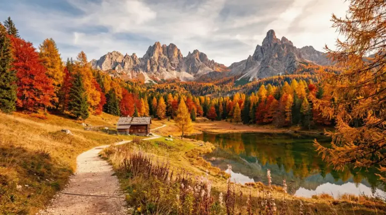 Paesaggio autunnale in Trentino con lago, bosco colorato e montagne sullo sfondo