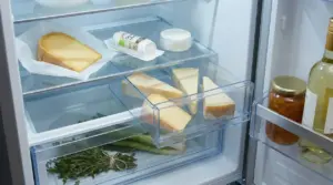 Formaggi e alimenti conservati correttamente all'interno di un frigorifero aperto