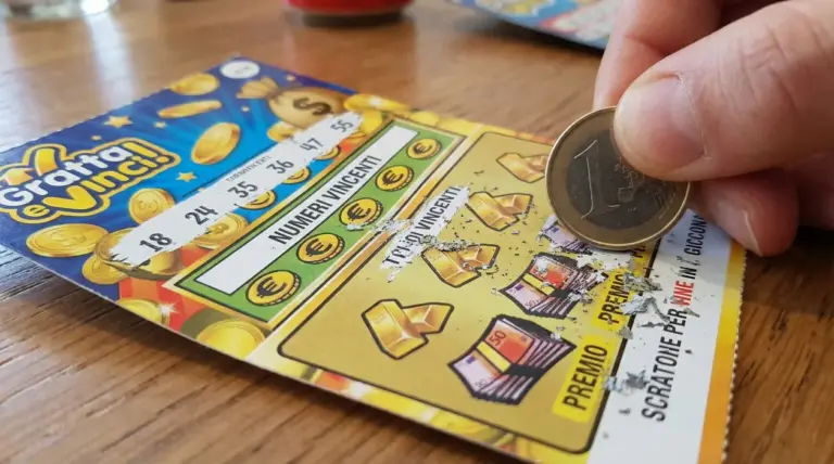 Una mano gratta un biglietto Gratta e Vinci con una moneta da un euro su un tavolo di legno