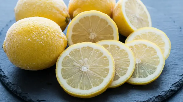 Fette e limoni interi congelati disposti su una superficie scura